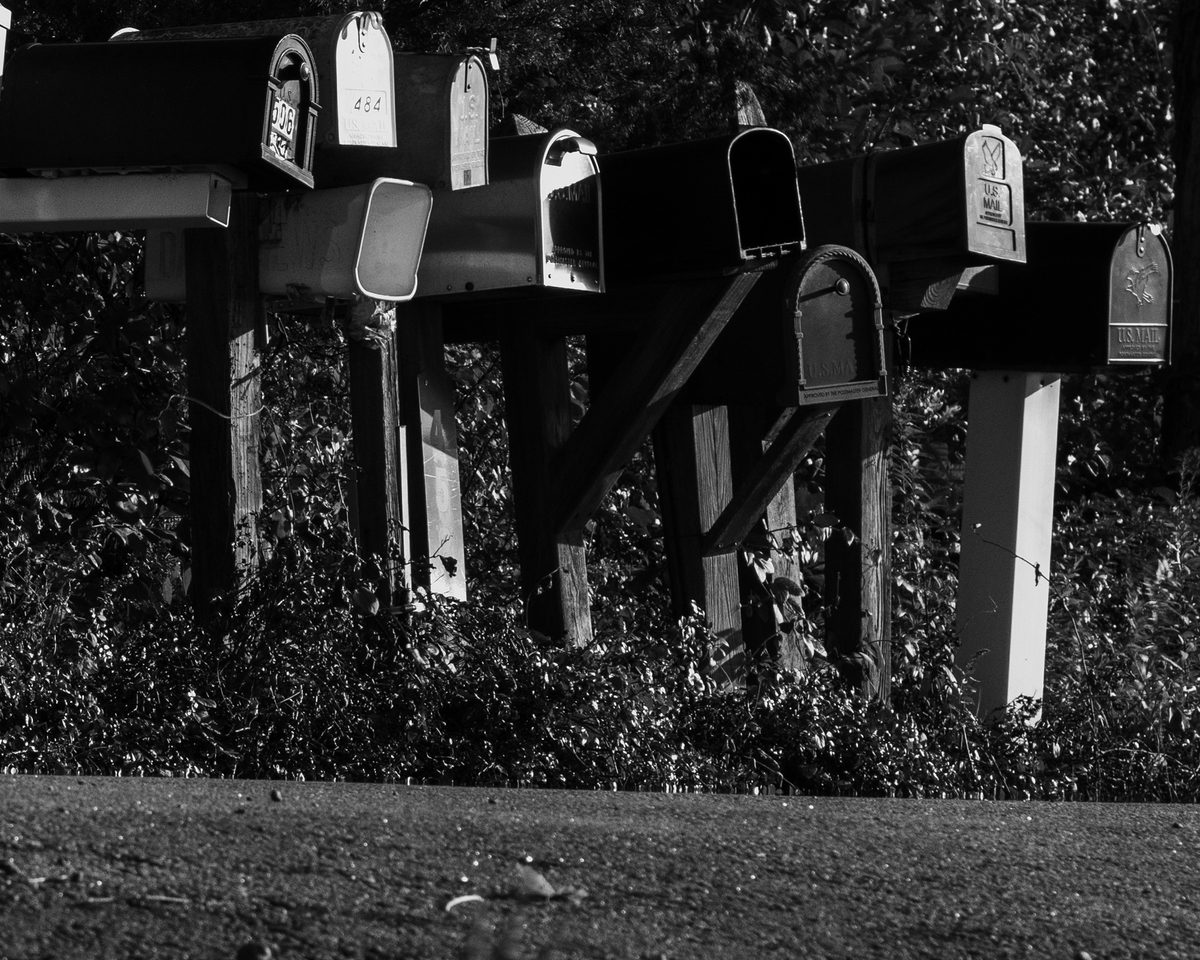 A row of roadside mailboxes in black and white